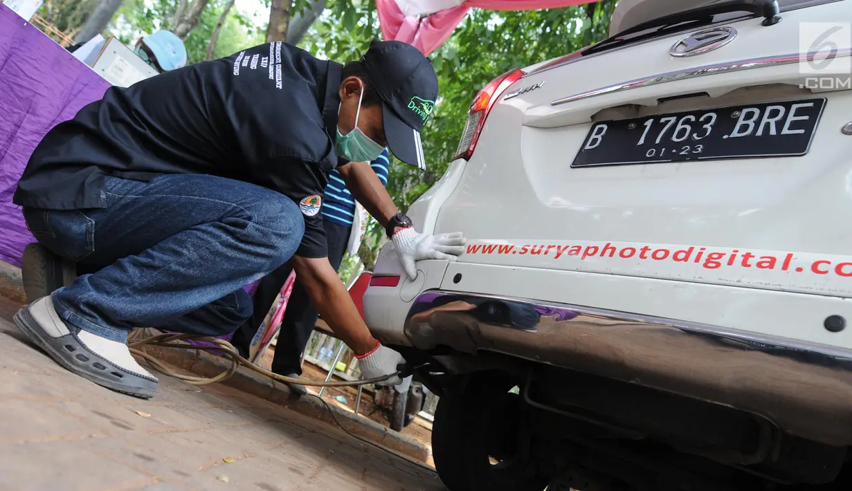 Petugas mengetes gas buang pada kegiatan uji emisi kendaraan di Taman Kota 1 BSD, Tangerang Selatan, Rabu (3/10). Dinas Lingkungan Hidup (DLH) Kota Tangerang Selatan menggelar uji emisi guna menekan angka polusi kendaraan. (Merdeka.com/Arie Basuki)