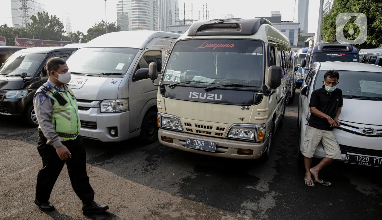 Polisi berjalan melewati kendaraan travel gelap yang disita jajaran Direktorat Lalu Lintas Polda Metro Jaya, Jakarta, Kamis (29/4/2021). Sebanyak 115 kendaraan travel gelap diamankan karena diduga kuat mengangkut pemudik di tengah masa pengetatan larangan mudik 2021. (Liputan6.com/Faizal Fanani)