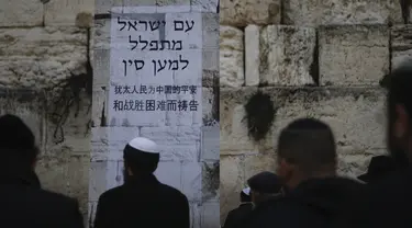 Orang-orang Yahudi berdiri di depan poster dalam bahasa Ibrani dan Tiongkok mengatakan, "Bangsa Israel berdoa untuk China." saat berdoa di Tembok Ratapan, situs paling suci di Kota Tua Yerusalem, Minggu, (16/2/2020). (AP Photo/Ariel Schalit)