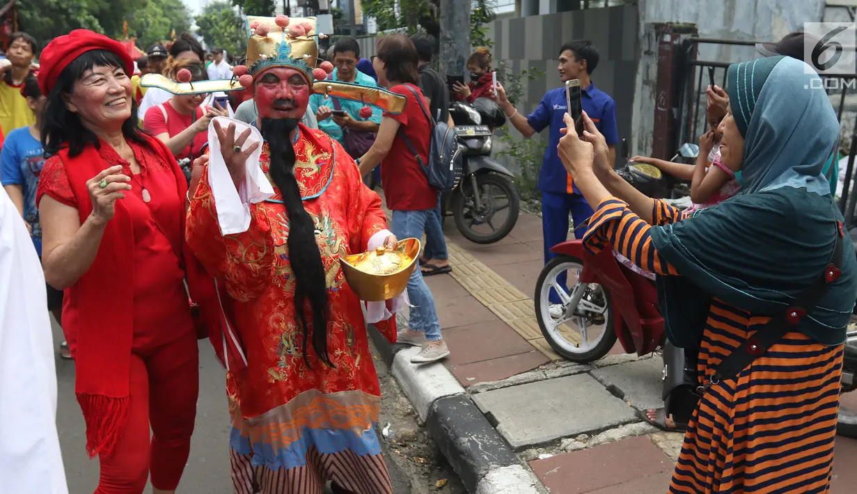 Warga mengambil gambar arak-arakan perayaan Cap Go Meh di kawasan Petojo, Jakarta, Selasa (19/2). Cap Go Meh merupakan perayaan hari ke-15 peringatan Tahun Baru China atau Imlek. (Liputan6.com/Angga Yuniar)