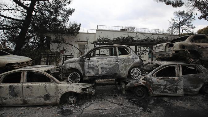 Mobil-mobil yang terbakar berserakan di sepanjang sisi jalan di Desa Mati, timur Athena, Selasa (24/7). Kebakaran hutan diperparan dengan embusan angin kencang. (AP Photo/Thanassis Stavrakis)