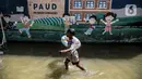 Seorang anak bermain air banjir rob di kawasan Muara Angke, Jakarta, Selasa (9/11/2021). Badan Penanggulangan Bencana Daerah (BPBD) DKI Jakarta memperkirakan puncak musim hujan dan potensi rob di Ibu Kota terjadi pada Januari hingga Februari 2022. (Liputan6.com/Faizal Fanani)