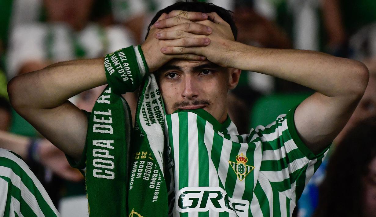 Seorang suporter Real Betis memegang kepalanya sambil meneteskan air mata sebagai bentuk kecewa atas kekalahan timnya dalam laga final UEFA Conference League melawan Chelsea di Tarczynski Arena, Wroclaw, Polandia, Kamis (29/05/2025) dini hari WIB. (AFP/Cristina Quicler)