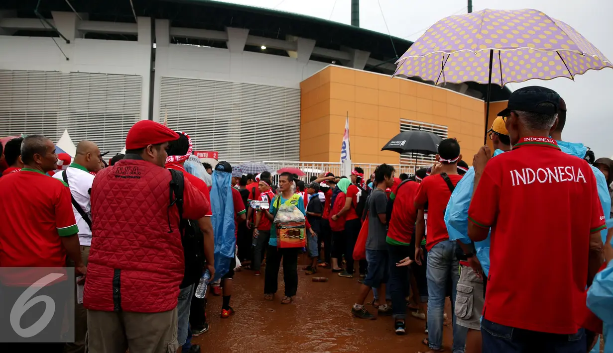 Ratusan orang mengantri untuk menonton pertandingan final leg pertama Piala AFF 2016 di Stadion Pakansari, Bogor, Rabu (14/12). Walau di guyur hujan, pendukung tetap semangat mendukung tim sepak bola Indonesia. (Liputan6.com/Johan Tallo)