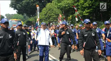 Menteri Komunikasi dan Informatika, Rudiantara (tengah) berlari membawa obor saat kirab obor Asian Games 2018 mengelilingi Kota Bogor, Jawa Barat, Selasa (14/8). Kota Bogor menjadi kota terakhir kegiatan pawai obor Asian Games. (Merdeka.com/Arie Basuki)