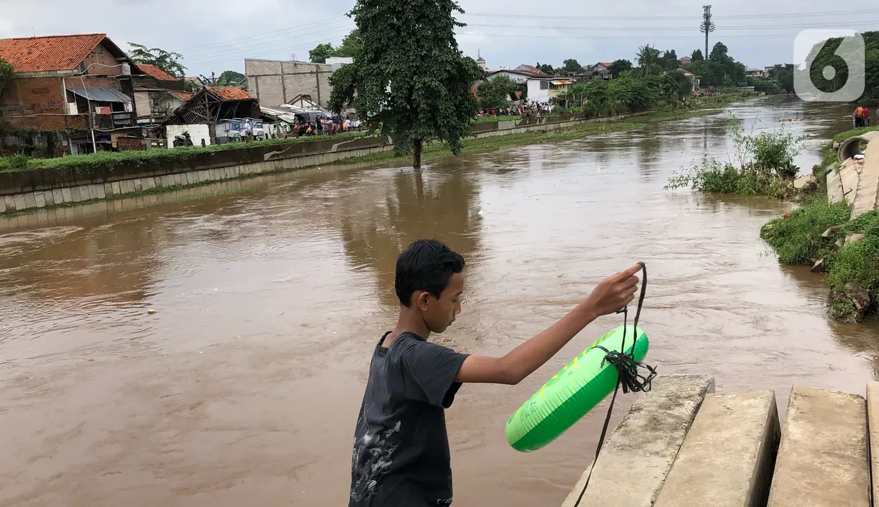 Seorang anak membawa ban karet di bantaran Sungai Ciliwung di kawasan Rawajati,  Jakarta, Selasa (25/2/2020). Adanya seorang warga yang hanyut saat berenang di tengah luapan Sungai Ciliwung tersebut mengundang perhatian warga serta petugas yang mencari keberadannya. (Liputan6.com/Immanuel Antonius)