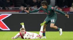 Gelandang Ajax Amsterdam Kenneth Taylor jatuh ke tanah di sebelah bek Liverpool Trent Alexander-Arnold pada matchday kelima Grup A Liga Champions 2022-2023 di Johan Cruiff Arena,  Kamis (27/10/2022) dini hari WIB. The Reds melaju usai menang telak 3-0 di kandang Ajax Amsterdam. (AP Photo/Peter Dejong)
