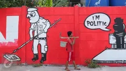 Warga melintasi mural bernuansa politik di Penjaringan, Jakarta, Minggu (7/8). Pesan-pesan yang disampaikan oleh mural politik ini biasanya bercermin dari kegiatan politik di Indonesia saat ini. (Liputan6.com/Angga Yuniar)