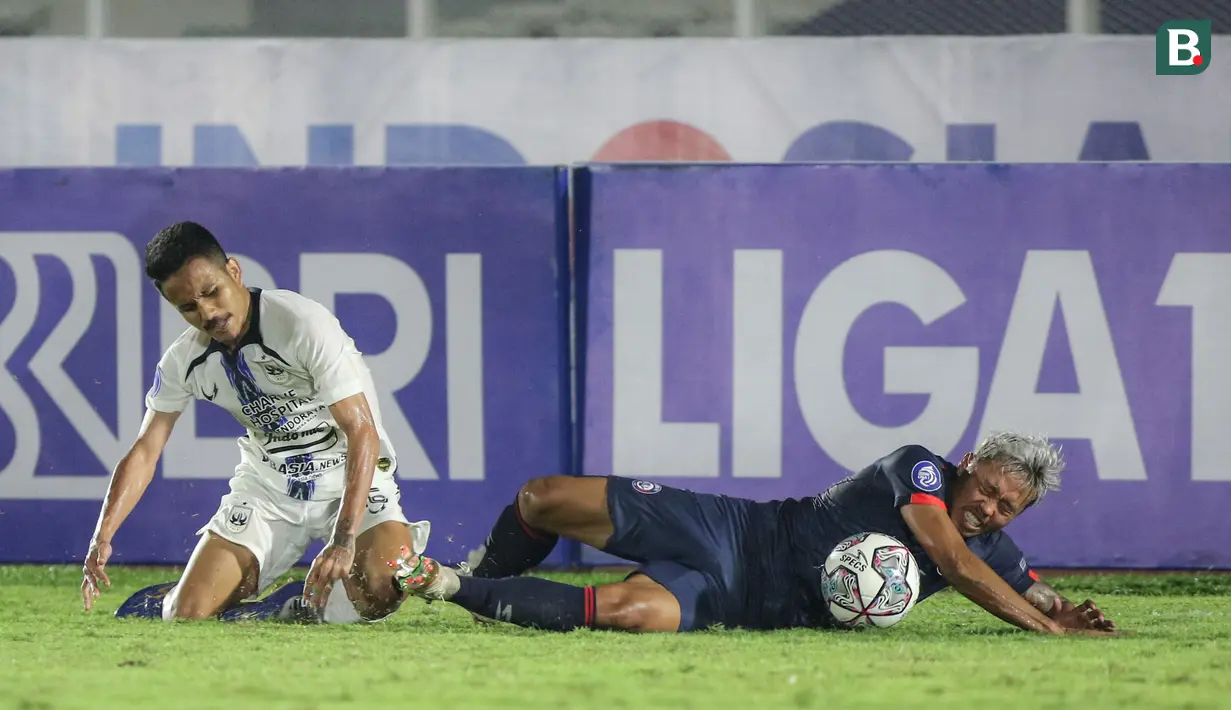 Pemain Arema FC, Kushedya Hari Yudo (kanan) terjatuh setelah berebut bola dengan pemain PSIS Semarang, Komarudin saat laga pekan keempat BRI Liga 1 2021/2022 di Stadion Madya, Jakarta. Arema FC harus puas bermain imbang tanpa gol saat bersua PSIS Semarang. (Bola.com/Bagaskara Lazuardi)