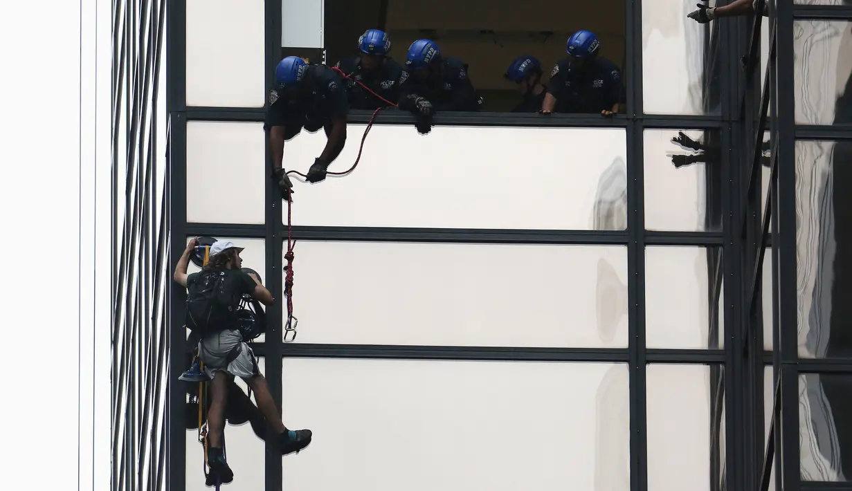 Sejumlah petugas NYPD bersiap menahan seorang pria yang memanjat gedung Trump Tower di New York, AS, Rabu (10/8). Petugas berhasil menangkap si pria berambut gondrong itu ketika mencapai lantai 21. (REUTERS/Carlo Allegri)
