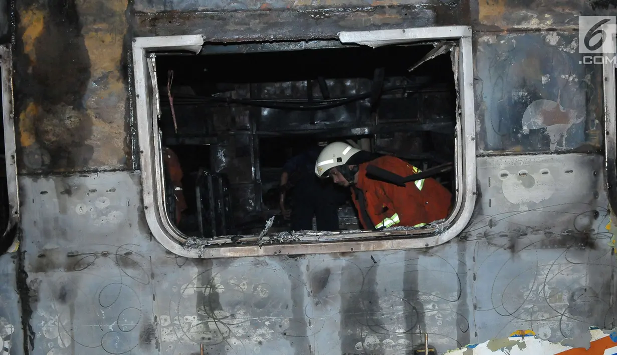 Petugas memeriksa kondisi dari gerbong kereta api yang terbakar usai terjadi tabrakan dengan mobil di perlintasan Kramat, Senen, Jakarta, Selasa (13/6). Belum ada kabar korban jiwa dalam peristiwa tersebut. (Liputan6.com/Helmi Afandi)