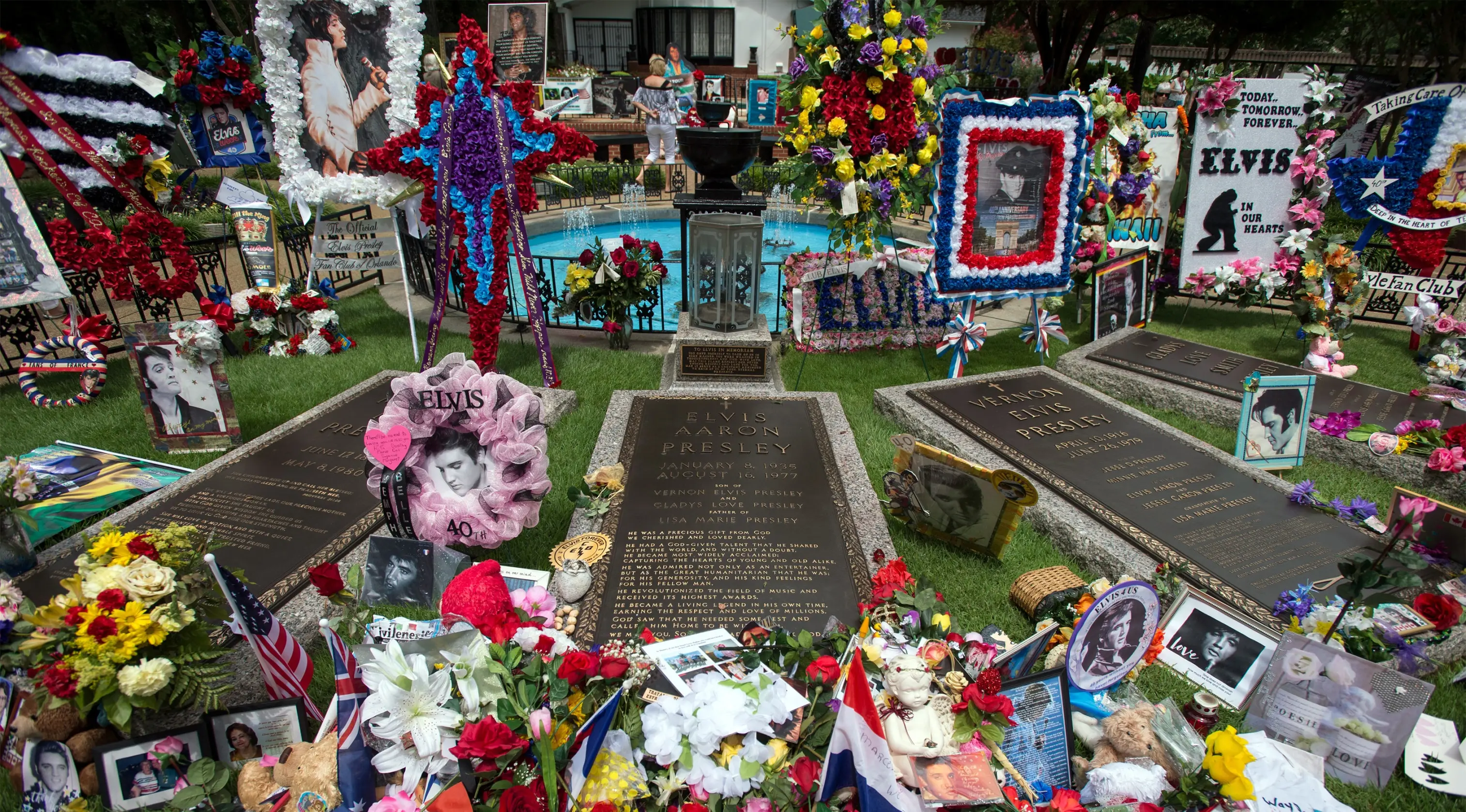 Karangan bunga beserta poster Elvis Presley memenuhi makam sang bintang rock n roll itu di Graceland, Memphis, Tennessee, Selasa (16/8). Elvis Presley menjadi salah satu ikon budaya paling penting di abad ke-20. (AP Photo/Brandon Dill)