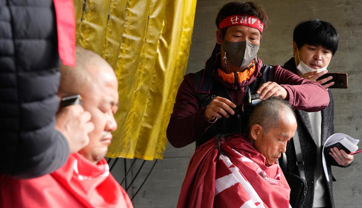 Anggota serikat Solidaritas Pengemudi Truk Kargo mencukur rambut mereka saat unjuk rasa menentang perintah pemerintah untuk kembali bekerja pada pengemudi truk semen di Uiwang, Korea Selatan, Selasa (29/11/2022). Undang-undang mengizinkan penggunaan perintah semacam itu untuk mengatasi gangguan transportasi yang serius dan jika tidak dipatuhi dapat menyebabkan hukuman seperti pembatalan lisensi pengemudi truk dan tiga tahun penjara, atau denda hingga 30 juta won ($22.550). (AP Photo/Ahn Young-joon)