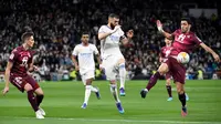 Pemain Real Madrid Karim Benzema (tengah) berebut bola dengan pemain Real Sociedad Jon Pacheco (kiri) dan Mikel Merino (kanan) pada pertandingan sepak bola Liga Spanyol di Stadion Santiago Bernabeu, Madrid, Spanyol, 5 Maret 2022. Real Madrid menang 4-1. (PIERRE-PHILIPPE MARCOU/AFP)