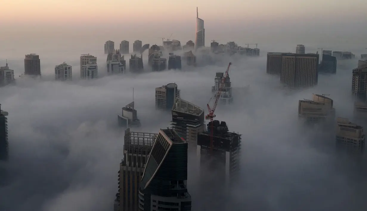 Saat gedung-gedung pencakar langit di selimuti kabut pagi di Kota Dubai, Uni Emirat Arab, Senin (5/12). Kota Dubai, terkenal dengan bangunan-bangunan mewah pencakar langit. Satu di antaranya adalah yang tertinggi di dunia, Burj Khalifa. (AFP/Rene Slama)