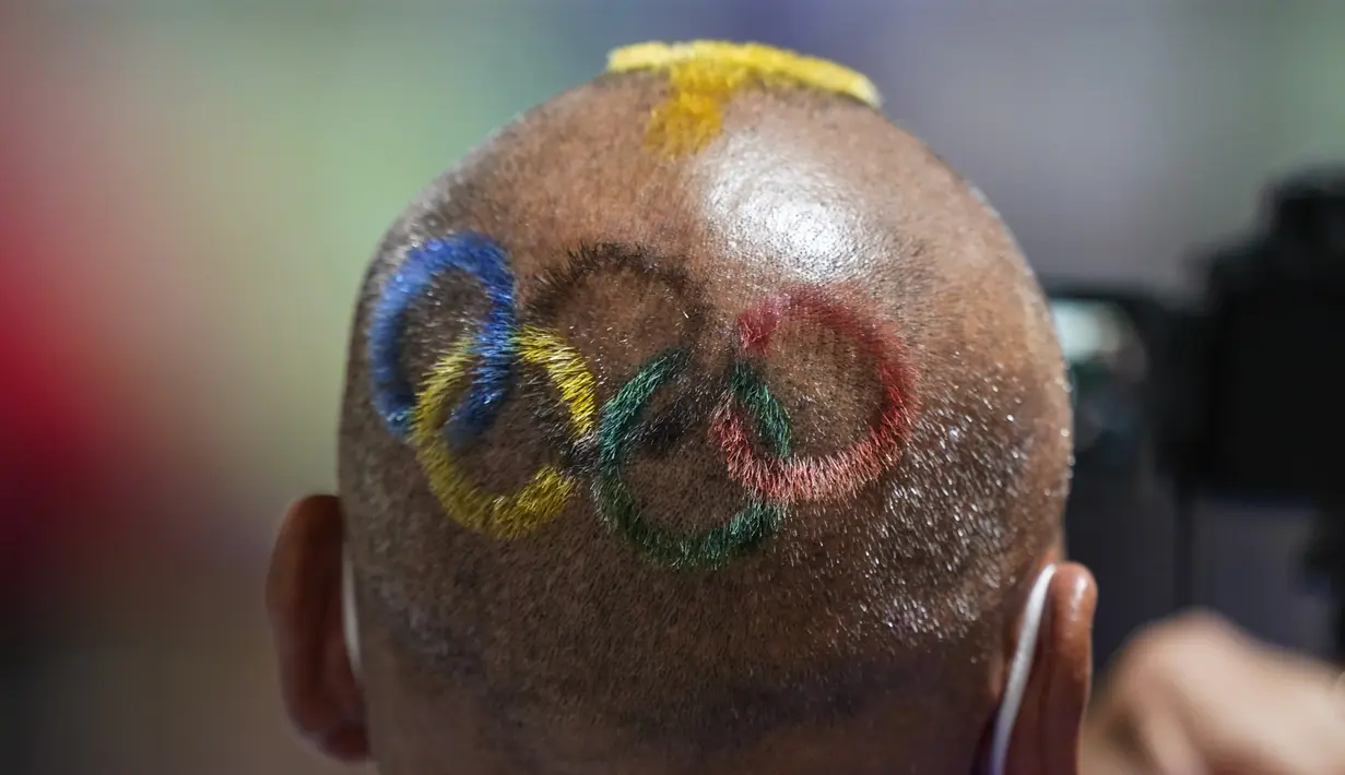 Pelatih Mongolia Undralbat Lkhagva mencukur dan mewarnai rambutnya dengan logo Olimpiade saat dia melihat pistol udara 10 meter putri dalam Olimpiade Tokyo 2020 di Asaka Shooting Range, Tokyo, Jepang, 25 Juli 2021. (AP Photo/Alex Brandon)