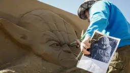 Seorang seniman patung saat membuat patung dari pasir yang berbentuk seperti pemeran Yoda dalam film Star Wars di Kazakhstan , 15 April 2016. Kebanyakan patung yang dibuat terinspirasi dari film - film Hollywood. (REUTERS / Shamil Zhumatov)