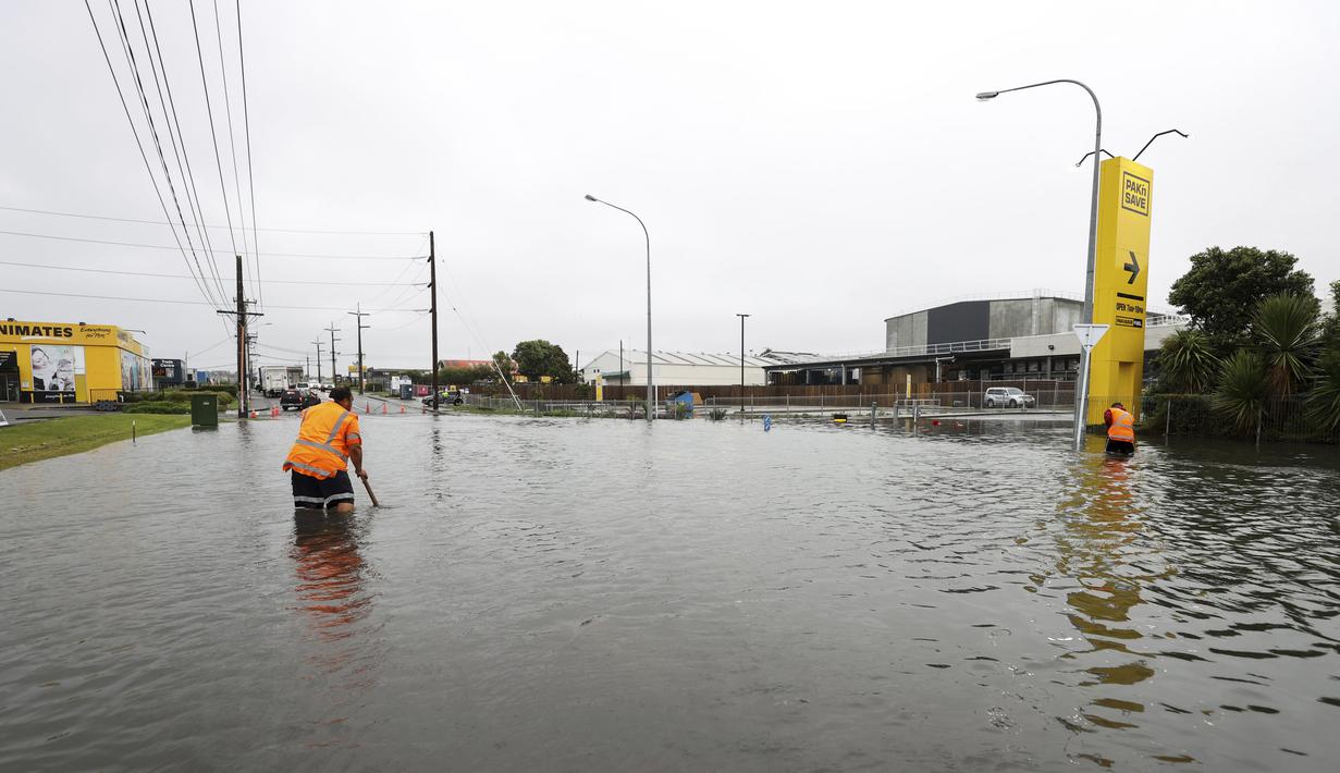 Para pekerja mencoba mensurvei tanah di bawah air banjir di Auckland, Selandia Baru, Rabu (1/2/2023). Peringatan hujan lebat untuk Auckland dicabut, meskipun keadaan darurat tetap berlaku untuk kota terbesar di negara itu setelah curah hujan dan banjir yang mencapai rekor. pada hari Jumat menewaskan empat orang dan menyebabkan gangguan yang meluas. (Brett Phibbs/New Zealand Herald via AP)