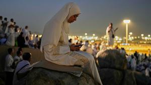 Seorang jemaah Muslim menggunakan telepon seluler untuk membaca ayat-ayat dari Al-Quran di atas bukit berbatu yang dikenal sebagai Jabal Rahmah atau Gunung Rahmat, di Dataran Arafah, selama ibadah haji tahunan di dekat kota suci Mekah, Arab Saudi, Selasa 26 Mei 2026. (AP Photo/Altaf Qadri)