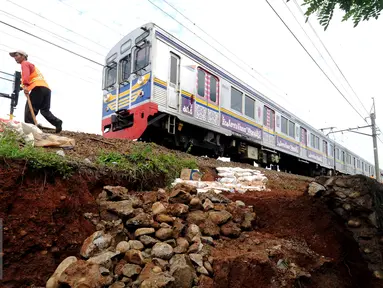 Pekerja meletakkan batuan untuk memperkuat struktur tanah yang longsor dekat rel KRL di sekitar Kampung Pabuaran, Bogor, Rabu (25/11/2015). Sebelumnya, Selasa (24/11) tanah di sekitar rel KM 38 dan 39 mengalami longsor. (Liputan6.com/Helmi Fithriansyah)