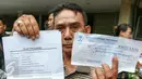 Korban penipuan program umroh PT SSI menunjukan bukti kwitansi dan surat pernyataan usai melakukan laporan di Polda Metro, Jakarta, Minggu (20/3/2016). Sebanyak 300-500 warga menjadi korban penipuan program umroh PT SSI. (Liputan6.com/Yoppy Renato)