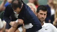 Ekspresi Novak Djokovic ketika mendapat perawatan medis pada lengan kanan saat melawan Adrian Mannarino pada Wimbledon 2017 di The All England Lawn Tennis Club, London, (11/7/2017). (AFP/Glyn Kirk)