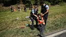 Polisi Prancis memindahkan sejumlah pengunjuk rasa lingkungan setelah aksi protes mereka menghentikan sementara balapan pada etape ke-10 Tour de France, antara Morzine dan Megeve, di Pegunungan Alpen Prancis, pada 12 Juli 2022. (AFP/Marco Bertorello)