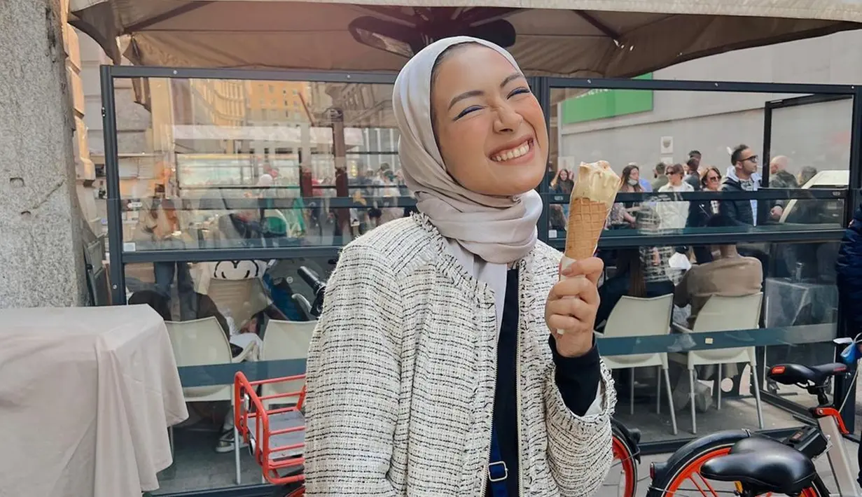Host yang sering muncul di televisi ini terlihat sumringah saat mencoba kuliner es krim saat berlibur di Italia. Milan terasa sangat menyenangkan bagi Bella Attamimi. Tak heran, senyum lebarnya terlihat saat menikmati enaknya rasa es krim yang dibelinya di toko pinggir jalan Milan. (Liputan6.com/IG/@bellattamimi)