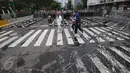 Pejalan kaki melintas dekat penjagaan ketat aparat kepolisian di sekitar Istana Negara, Jakarta, Jumat (31/3). Dalam upaya antisipasi ricuh aksi 31 Maret, polisi menutup seluruh akses jalan menuju Istana Negara. (Liputan6.com/Immanuel Antonius)