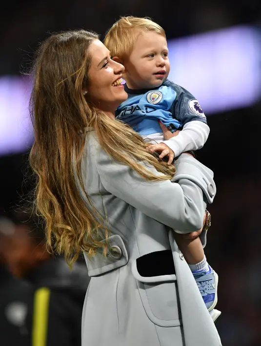 Istri Pablo Zabaleta menggendong putranya Asier usai pertandingan melawan West Bromwich Albion di Liga Inggris di Stadion Etihad, Manchester,(16/5). Zabaleta telah membela Man City selama 9 tahun. (AFP Photo/Anthony Devlin)