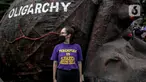 Seorang massa aksi berdiri dekat replika gurita raksasa oligarki saat aksi di Patung Kuda, Jakarta, Selasa (8/3/2022). Aksi tersebut untuk memperingati Hari Perempuan Internasional serta menuntut pengesahan RUU TPKS yang partisipatif dalam pembahasan dan pro korban. (Liputan6.com/Faizal Fanani)