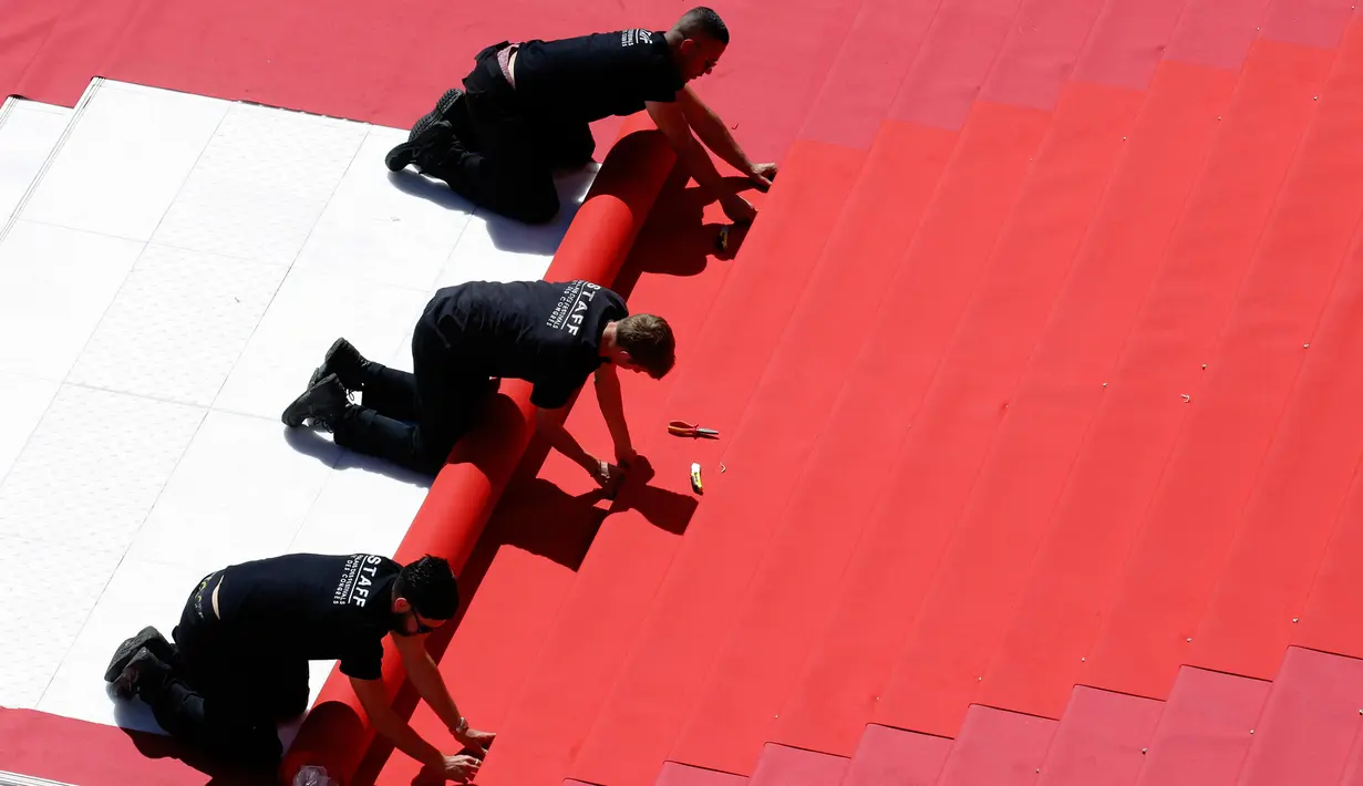 Pekerja memasang karpet merah di depan pintu masuk utama jelang upacara pembukaan Festival Film Cannes 2019 di Cannes, Prancis, Selasa (14/5/2019). Terdapat 1.845 film panjang yang akan ditayangkan dalam Festival Film Cannes 2019. (REUTERS/Regis Duvignau)