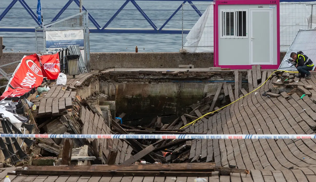 Petugas polisi mengambil foto di lokasi robohnya platform panggung dari kayu pada festival musik di tepi laut di Vigo, Spanyol, Senin (13/8). Panggung tiba-tiba runtuh saat pengunjung sedang menonton seorang artis rap lokal, Rels B. (AP/Lalo R. Villar)