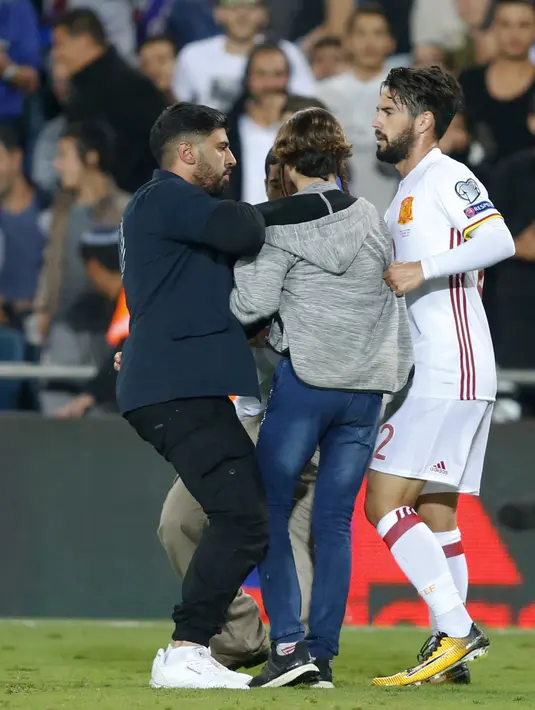 Petugas membawa pria yang mendekati Isco saat pertandingan Israel melawan Spanyol di Stadion Teddy di Yerusalem (9/10). Polisi Israel membantah laporan media lokal bahwa seorang suporter membawa pisau. (AP Photo/Ariel Schalit)