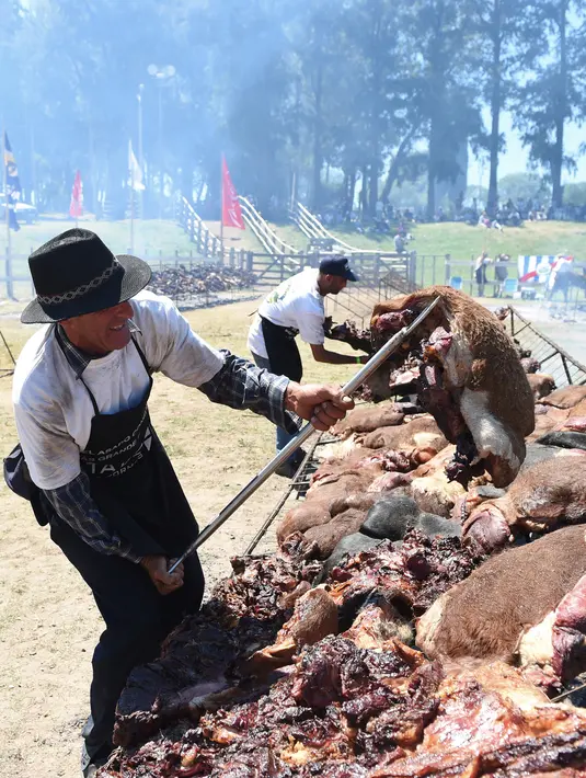 Peserta membalikan daging sapi yang sedang dipanggang di Taman Rodo di Minas, Uruguay (10/12). Dengan daging sebanyak 16.500 kg, mereka berusaha memecahkan rekor dunia dengan katagori  "The World's Biggest Barbecue". (AFP Photo/Miguel Rojo)