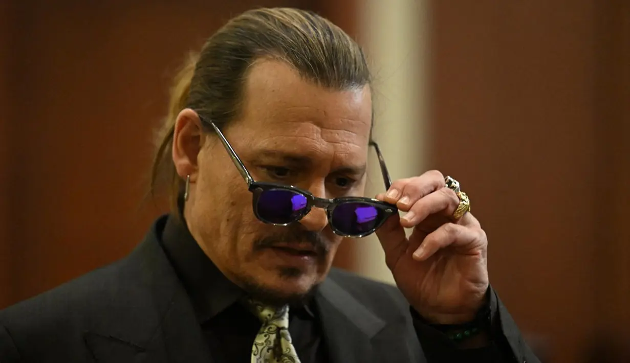 Aktor Johnny Depp mengenakan kacamata hitam saat persidangan pencemaran nama baik di Fairfax County Circuit Courthouse, Fairfax, Virginia, Amerika Serikat, 19 April 2022. Amber Heard menyebut Johnny Depp sebagai “figur publik yang mewakili kekerasan dalam rumah tangga.” (JIM WATSON/POOL/AFP)