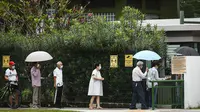 Para pemilih mengenakan masker dan menerapkan jaga jarak aman saat akan memberikan suara dalam pemilu di TPS Sekolah Dasar Alexandra, Singapura, Jumat (10/7/2020). Pemilu di tengah pandemi COVID-19, warga Singapura memberikan suaranya dengan mengenakan masker dan sarung tangan plastik. (AP Photo)