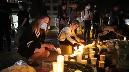 Para pengunjuk rasa menyalakan lilin untuk memberi penghormatan kepada mahasiswa Alex Chow Tsz-lok di Hong Kong (8/11/2019). Alex Chow Tsz-lok, 22 tahun, merupakan mahasiswa ilmu komputer dari mahasiswa Hong Kong University of Science and Technology. (AP Photo/Kin Cheung)