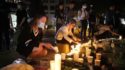 Para pengunjuk rasa menyalakan lilin untuk memberi penghormatan kepada mahasiswa Alex Chow Tsz-lok di Hong Kong (8/11/2019). Alex Chow Tsz-lok, 22 tahun, merupakan mahasiswa ilmu komputer dari mahasiswa Hong Kong University of Science and Technology. (AP Photo/Kin Cheung)