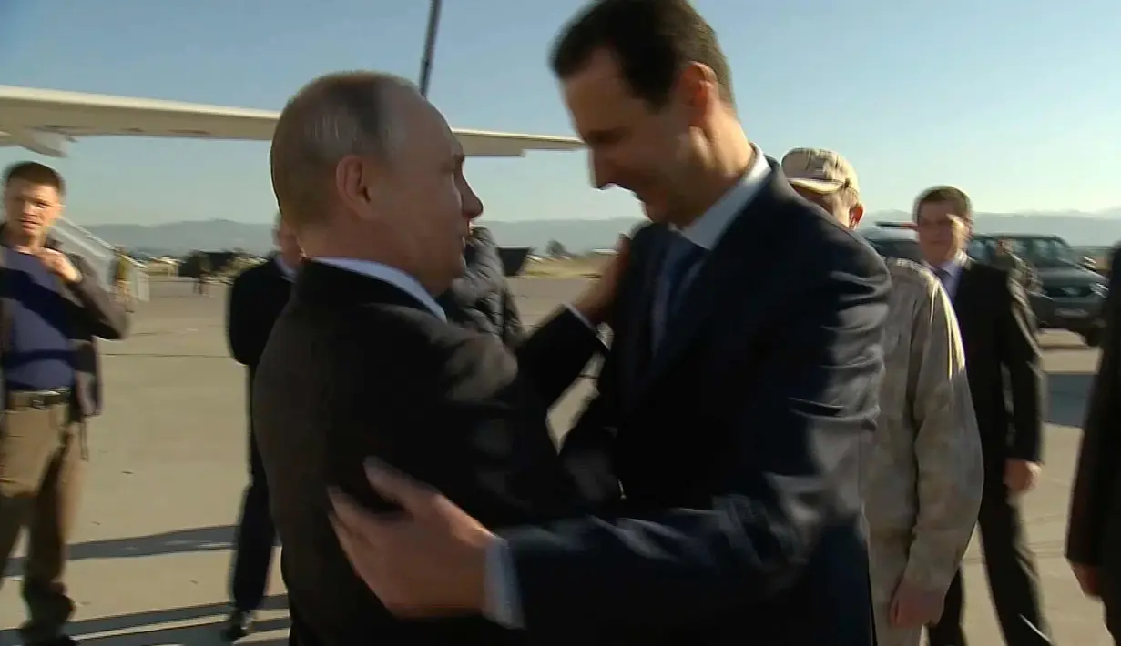 Presiden Suriah Bashar Assad memeluk Presiden , Vladimir Putin saat tiba di pangkalan udara Hemeimeem di Suriah (11/12). (Presidential TV photo via AP)