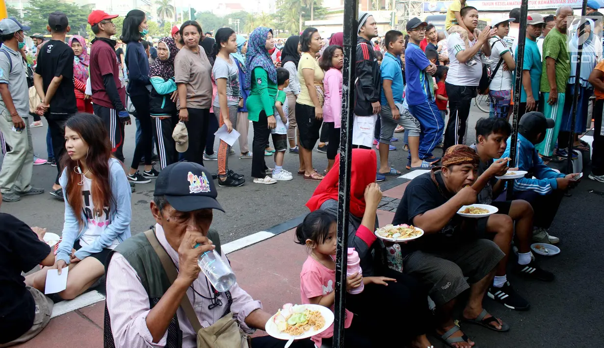 Warga memakan nasi goreng gratis ala prajurit Korps Marinir TNI AL saat car free day di Jakarta, Minggu (5/11). Kegiatan bagi-bagi nasi goreng ini dalam rangka menyambut HUT Marinir ke-72. (Liputan6.com/Angga Yuniar)