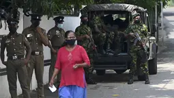 Pejalan kaki melewati Satuan Tugas Khusus (STF) dan personel polisi yang berjaga di sepanjang jalan di Kolombo pada Sabtu (2/4/2022). Pasukan militer dikerahkan di Sri Lanka, beberapa jam setelah presiden mengumumkan keadaan darurat ketika protes terhadapnya meningkat. (KODIKARA / AFP)