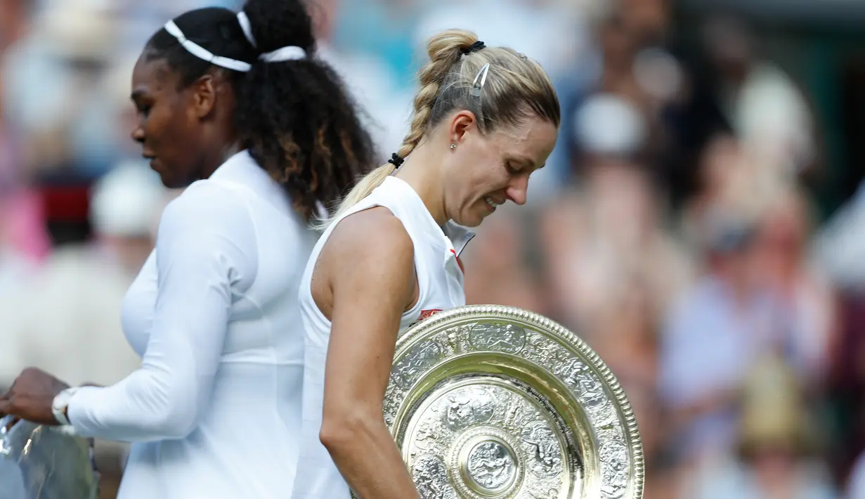 Petenis Jerman, Angelique Kerber (kanan) membawa trofi usai mengalahkan petenis AS, Serena Williams pada final tunggal putri kejuaraan Tenis Wimbledon 2018 di London, (14/7). Kerber menang atas Williams 6-3,6-3. (AP Photo/Nic Bothma)