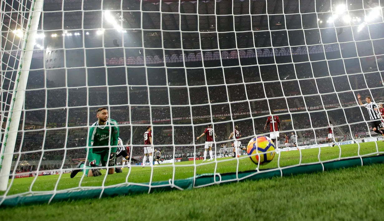 Kiper AC Milan, Gianluigi Donnarumma mengamati bola yang gagal ditangkapnya dalam lanjutan Serie A Italia melawan Juventus di Stadion San Siro, Sabtu (28/10). Dua gol Si Nyonya Tua diborong striker Gonzalo Higuain. (AP/Luca Bruno)