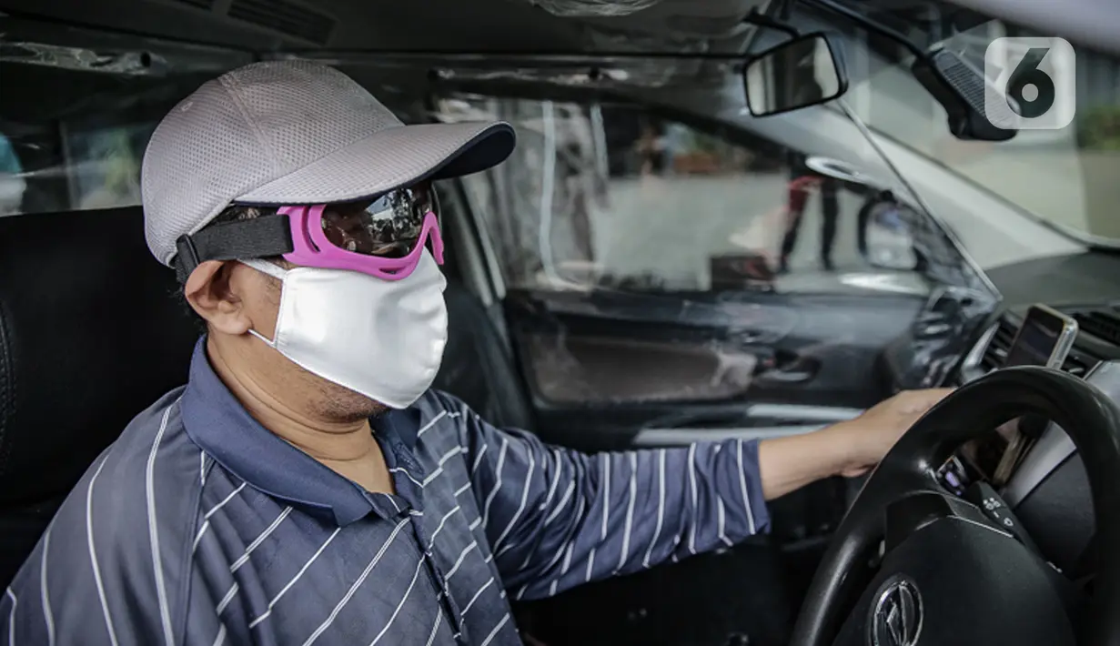 Pengemudi taksi daring, Aris Hardy Halim menunggu calon penumpang di dalam mobilnya yang telah terpasang plastik pembatas di kawasan Bendungan Hilir, Jakarta, Jumat (8/5/2020). (Liputan6.com/Faizal Fanani)
