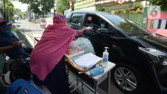Guru SDIT Ibnu Sina memberikan tugas sekolah secara drive-thru kepada wali murid di Jakarta, Rabu (26/8/2020). Selama pembelajaran jarak jauh, siswa diwajibkan mengambil dan mengembalikan tugas di sekolah. (merdeka.com/Imam Buhori)