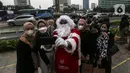 Seorang berpakaian sinterklas berfoto dengan warga saat acara Christmas in Jakarta di Bundaran Hotel Indonesia, Jakarta, Selasa (21/12/2021). Pemerintah Provinsi DKI Jakarta menggelar Christmas in Jakarta dalam rangka menyambut Natal 2021. (Liputan6.com/Johan Tallo)