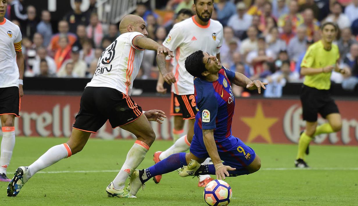 Striker Barcelona, Luis Suarez, dijatuhkan bek Valencia, Aymen Abdennour, pada laga La Liga di Stadion Mestalla, Valencia, Sabtu (22/10/2016). Barcelona menang 3-2 atas Valencia. (AFP/Jose Jordan)