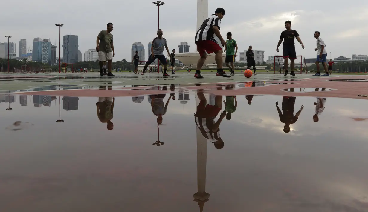 Sejumlah warga berebut bola saat olahraga sepak bola di Kawasan Monumen Nasional, Jakarta, Rabu (13/2). Monas merupakan salah satu lokasi yang kerap dijadikan ruang olahraga bagi warga ibukota. (Bola.com/M. Iqbal Ichsan)