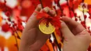 Koin diletakan di Instalasi Red Lunar di Mal Senayan City, Jakarta, Kamis (19/1/2023). Pengunjung bisa menikmati Instalasi yang indah ini mulai dari 14 Januari – 5 Februari 2023. (Liputan6.com/Herman Zakharia)